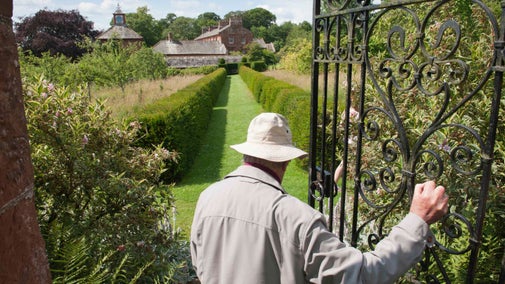 Visitor going through the gate to the orchard at Acorn Bank Garden, Cumbria, in August